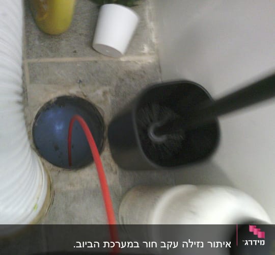 צינור אדום ליד פתח ניקוז על רצפה אפורה